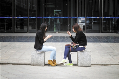 ②海淀图书城附近,两位女孩面对面坐着,玩着各自的手机.
